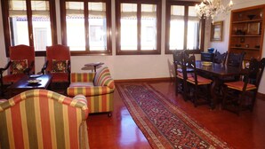 A spacious living room with a large rug, striped sofas, a dining table with chairs, and a chandelier. - Panoramic view in San Marco overlooking the rooftops (Venezia)