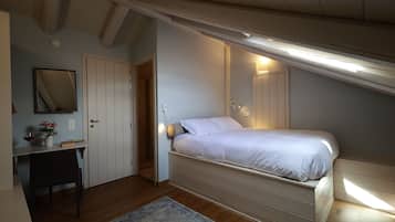 Un dormitorio con cama, escritorio, silla, espejo y puerta.