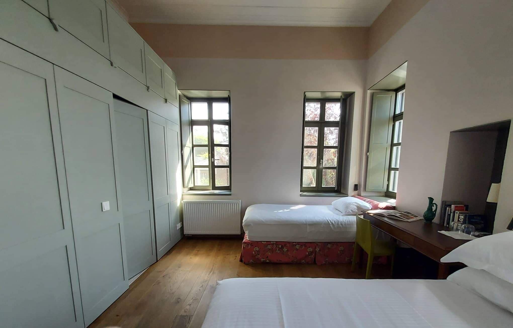 A bedroom with two beds, a radiator, and a window.