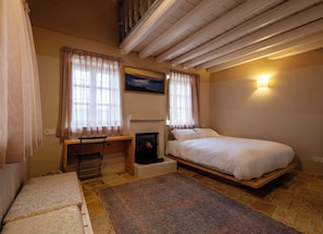 A bedroom with a bed, a desk, a chair, a fireplace, and a large rug.