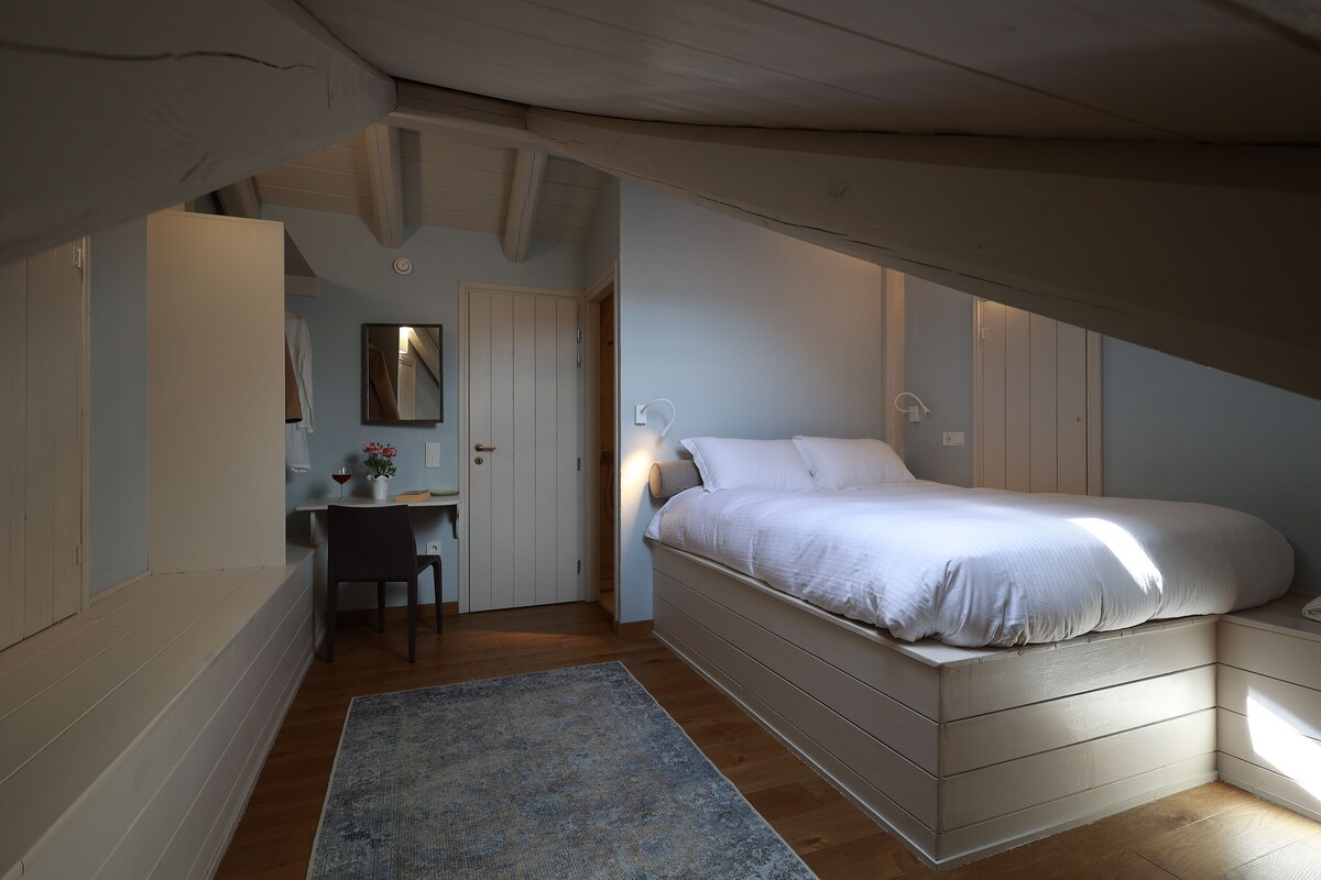 A bedroom with a bed, a desk, and a chair.