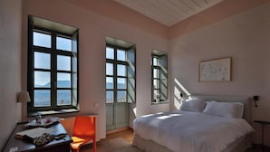 Um quarto com uma cama grande, uma escrivaninha com cadeira e uma janela com vista.