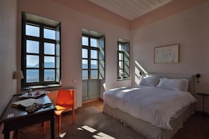 Un dormitorio con una cama grande, un escritorio con silla y una ventana con vistas.
