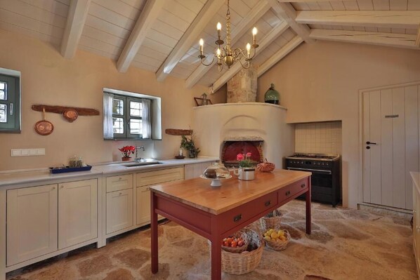 A kitchen with a wooden table, a built-in oven, and a hanging chandelier.
