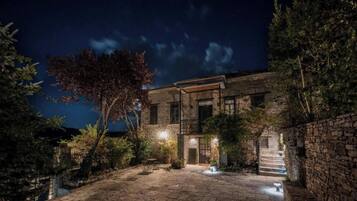 A stone building with a staircase leading to the entrance, surrounded by trees and a clear night sky.