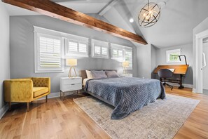 A bedroom with a bed, bedside lamps, a desk, and a chair. - Above Nashville West End Rhythm | Music Studio | Premium Location | Luxe (Nashville)