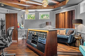 A music studio with a central mixing console, a blue couch, and a guitar wall. - Above Nashville West End Rhythm | Music Studio | Premium Location | Luxe (Nashville)