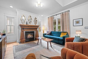 A living room with a fireplace, a sofa, a coffee table, and a view of the outdoors. - Above Nashville West End Rhythm | Music Studio | Premium Location | Luxe (Nashville)