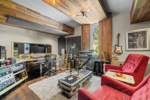 A music studio with a mixing console, keyboard, guitars, and a red armchair. - Above Nashville West End Rhythm | Music Studio | Premium Location | Luxe (Nashville)