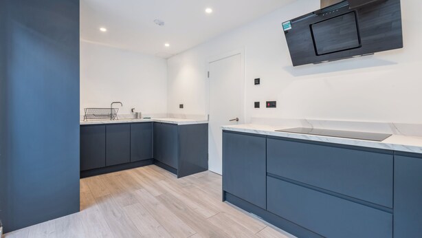A modern kitchen with dark cabinetry, a white countertop, and a built-in oven. - Bright Modern 3BDR Family Home with Private Patio (Greater London)