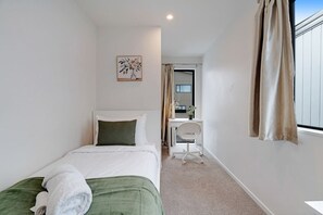 A hotel room with a bed, a desk, and a chair.