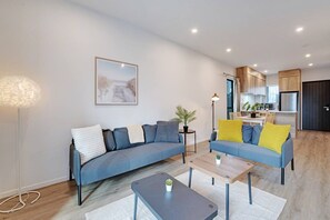 A modern living room with a sofa, coffee table, and a painting on the wall.