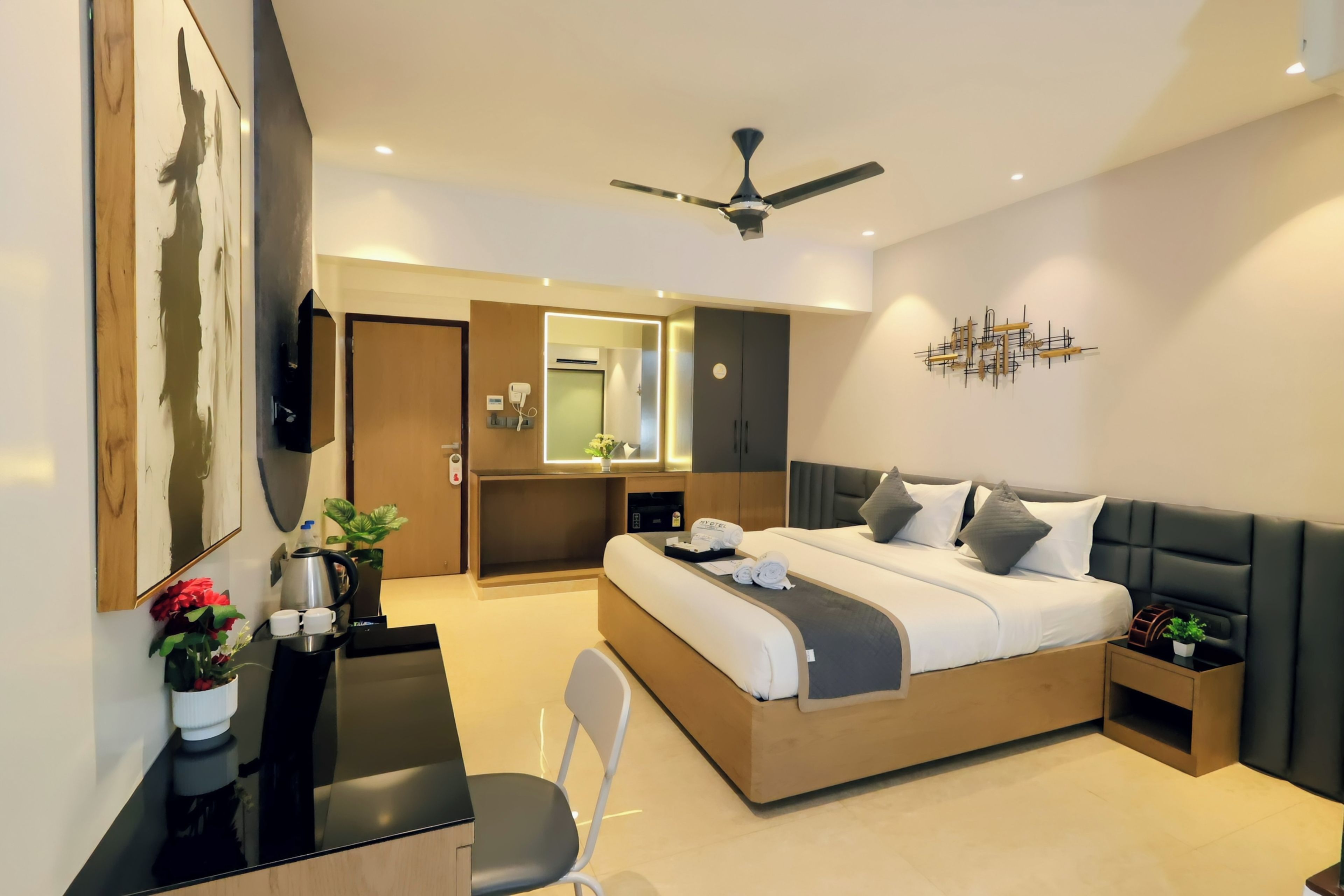 Una habitación de hotel moderna con cama, escritorio, silla y ventilador de techo.