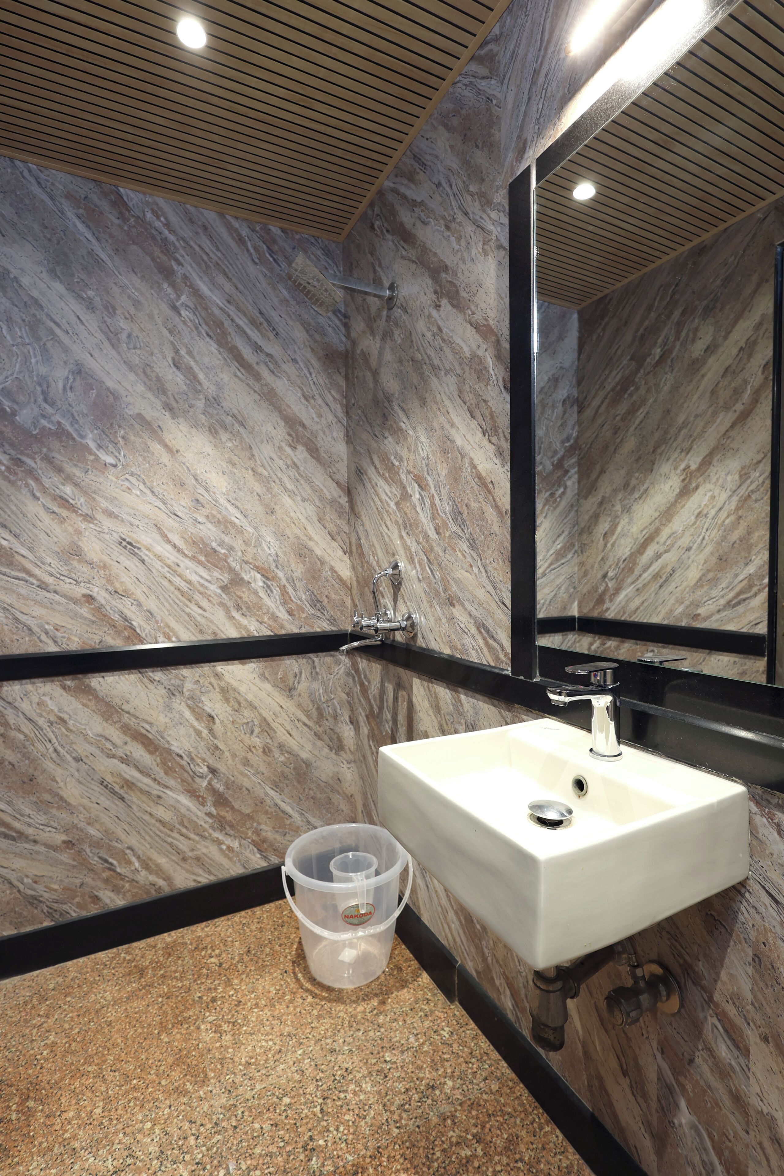 A bathroom with a marble wall, a white sink, and a mirror.