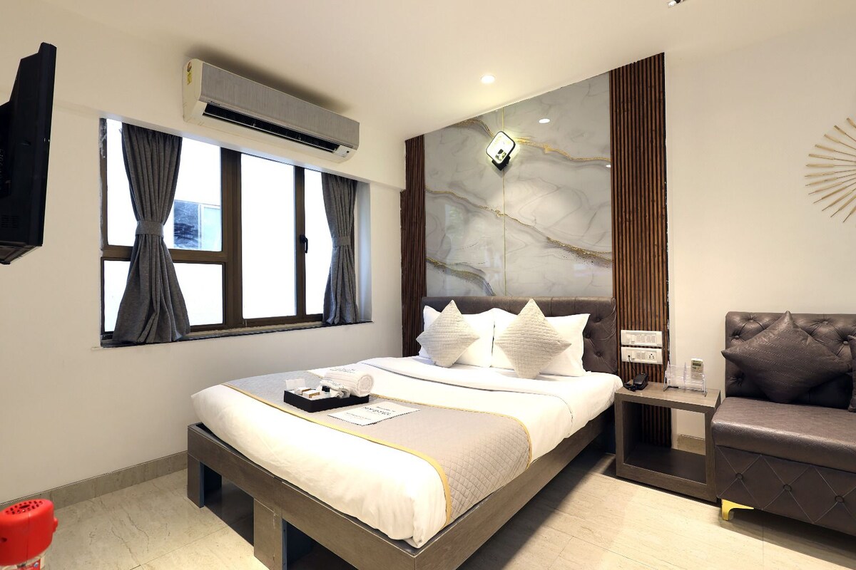 Una habitación de hotel moderna con cama, mesita de noche y zona de estar.