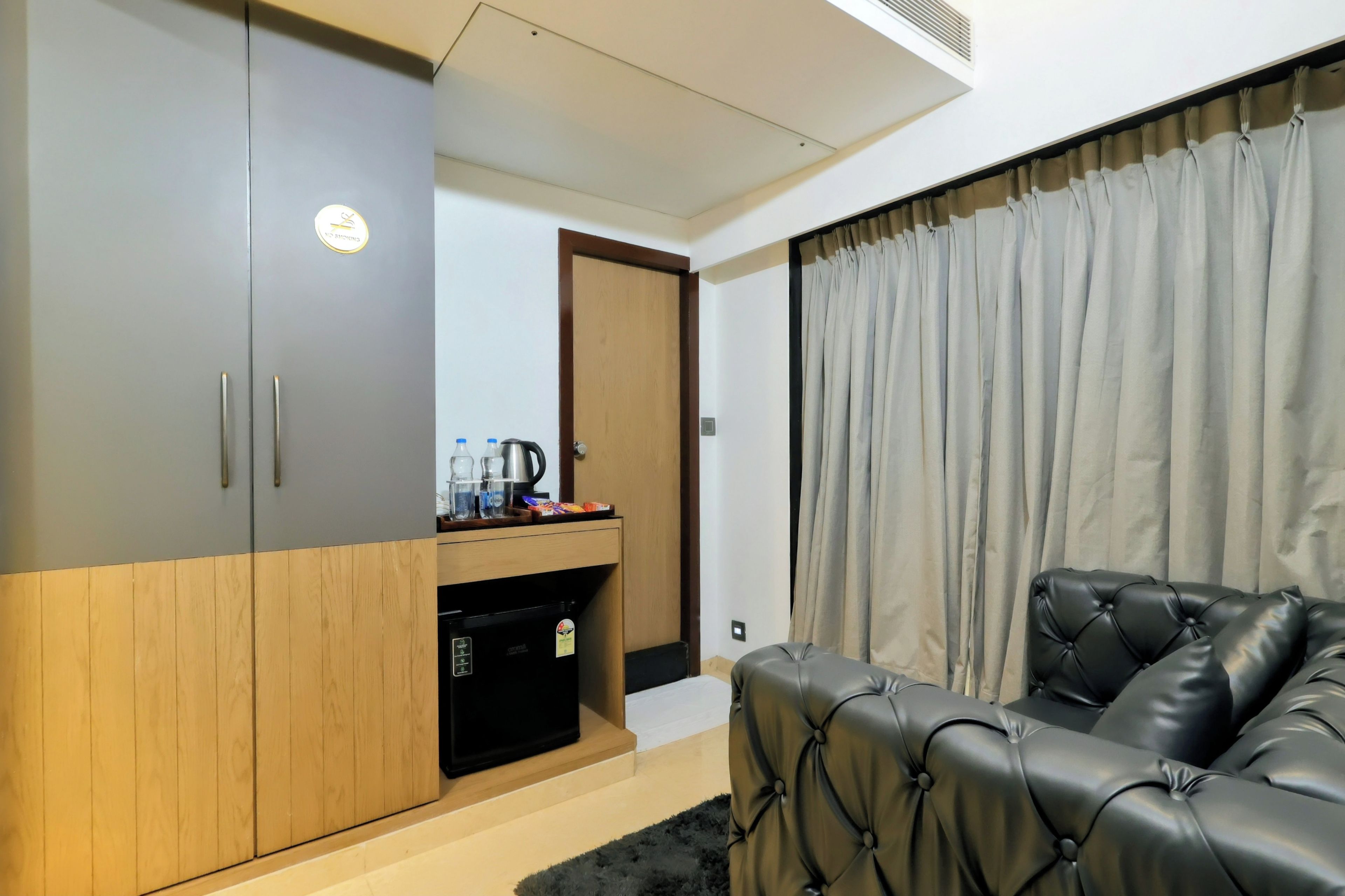 A modern room with a sofa, a wardrobe, a coffee maker, and a kettle on a counter.