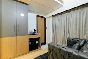 Una habitación moderna con sofá, armario, cafetera y hervidor sobre una encimera.