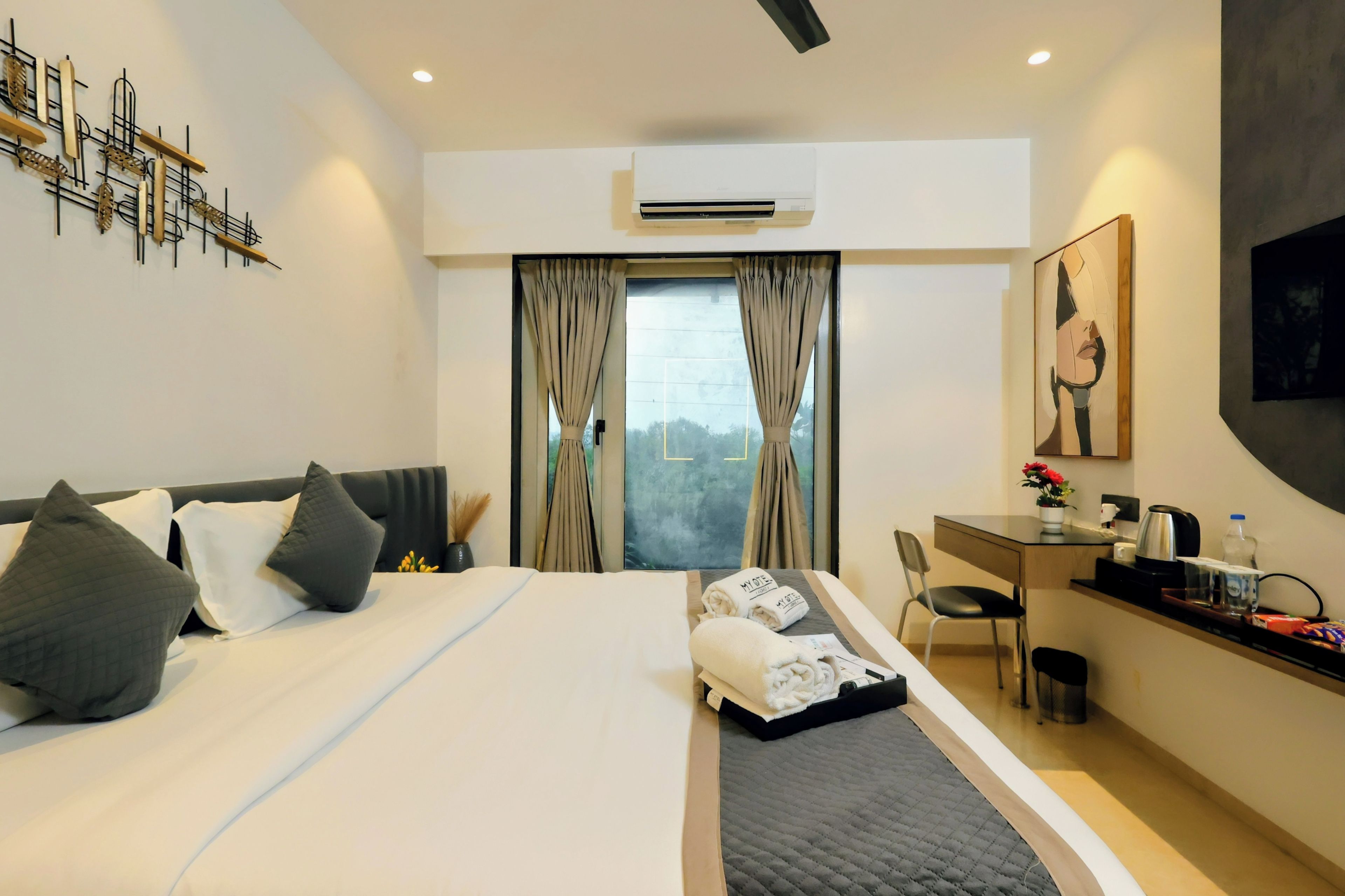 A modern hotel room with a large bed, a desk, and a view through the window.