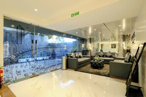 A modern hotel lobby with a large cityscape mural, plush seating, and a clear emergency exit sign.