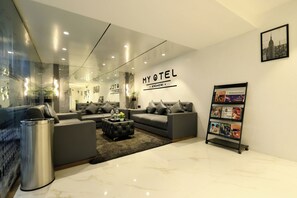 A modern hotel lobby with a sofa set, a coffee table, and a magazine rack.