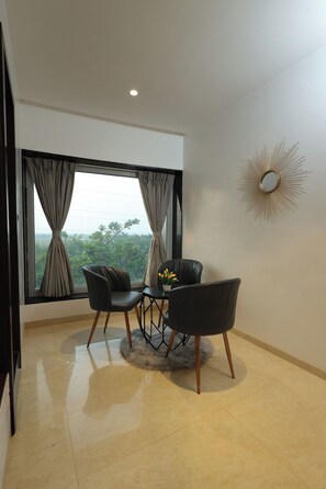 A room with a dining table, two chairs, a decorative mirror, and a view of greenery outside. - Myotel - Andheri (Mumbai)