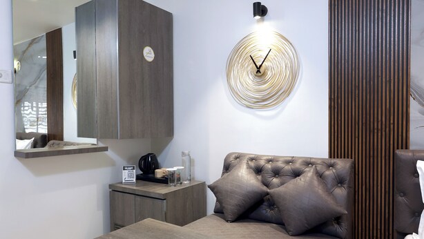 A modern bedroom with a bed, a bedside table, a wall clock, and a mirror. - Myotel - Andheri (Mumbai)