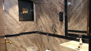 A modern bathroom with a marble wall, a black countertop, a white sink, and a toilet. - Myotel - Andheri (Mumbai)