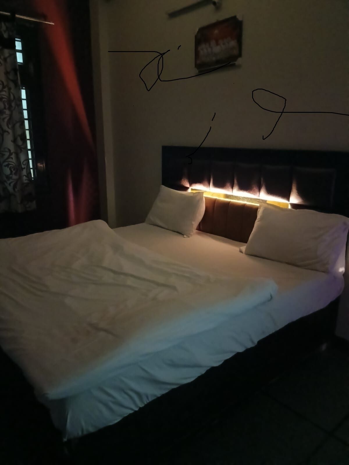 Un lit avec une literie blanche et une tête de lit dotée d’un éclairage intégré.