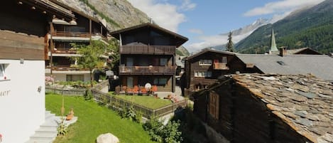 A traditional chalet-style building with a wooden facade, a balcony, and a stone roof.