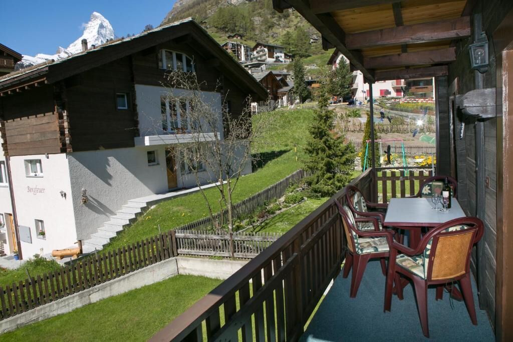 A chalet with a balcony, wooden exterior, and a view of a mountain.