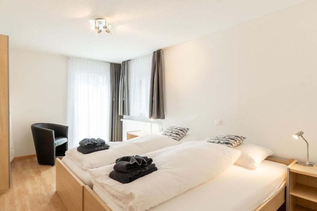 Ein Hotelzimmer mit Bett, Nachttisch, Lampe und einem Sessel.