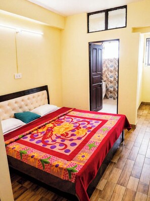 A room with a bed, a door, a window, and a wall socket. - Hotel Himalayan Darshan Retreat Berinag (Berinag)