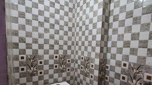 Een badkamer met een zwart-wit betegelde vloer, toilet, douchetoilet en wastafel.
