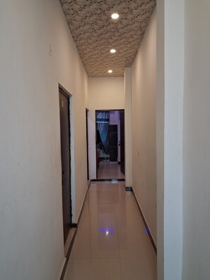 A corridor with a tiled floor, a door on the left, and a light fixture on the ceiling. - Ladli homes  (Mathura)
