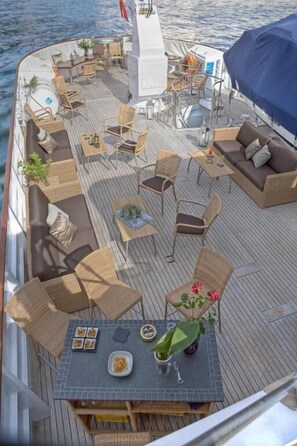 A boat deck with outdoor seating, a covered area, and a dining table with food. - Sanssouci Star - Exclusive Island Cruise (Flensburg)