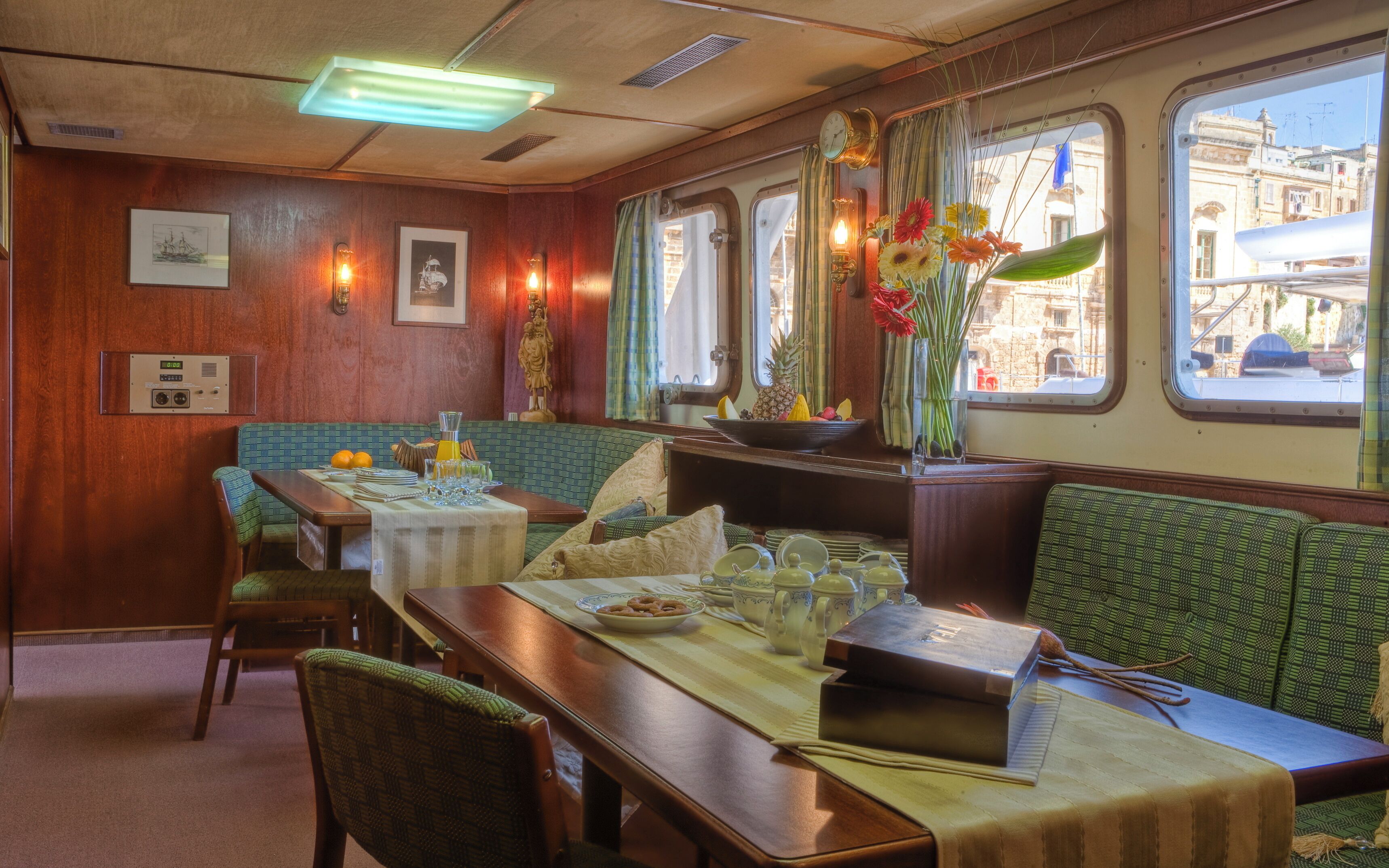 Un coin repas avec des murs en bois, une table dressée avec des assiettes, des verres et un vase rempli de fleurs.