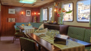 A dining area with wooden walls, a table set with plates, glasses, and a vase of flowers. - Sanssouci Star - Exclusive Island Cruise (Flensburg)