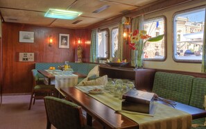 A dining area with wooden walls, a table set with plates, glasses, and a vase of flowers. - Sanssouci Star - Exclusive Island Cruise (Flensburg)