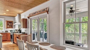 A dining area with a long table, white chairs, and a view of the outdoors. - NEW RENTAL!  Visit 'Lazy Lake Days"! (Huddleston)