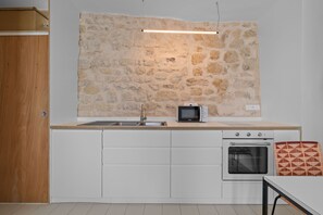 Eine Küche mit Steinwand, Mikrowelle, Backofen und Spüle.