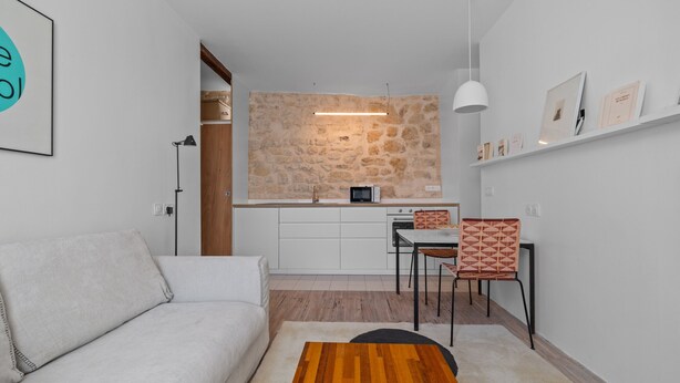 A modern living space with a sofa, a dining area with chairs, a kitchen with a stone backsplash, and a white ceiling. - Nid d'Ivresse, 1BR/1BA, 2 people (Paris)