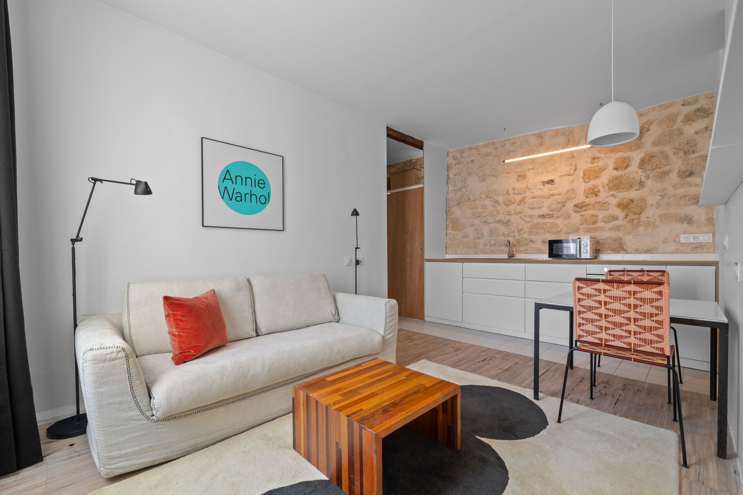 Uma sala de estar moderna com um sofá, uma mesa de centro e uma área de jantar com uma cadeira.