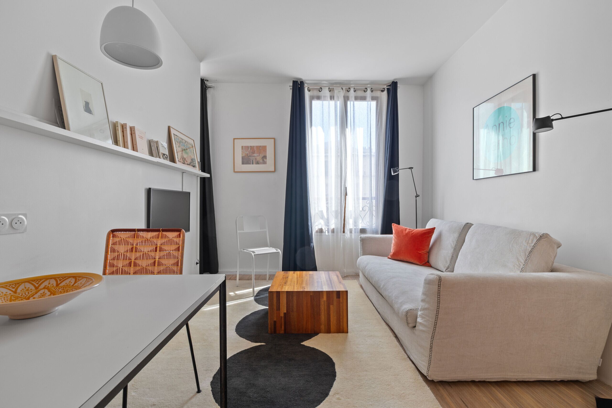 A modern living room with a sofa, a coffee table, a TV, and a bookshelf.