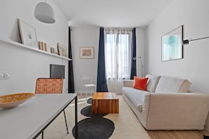 Ein modernes Wohnzimmer mit einer Couch, einem Couchtisch, einem Fernseher und einem Bücherregal.