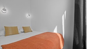 A bedroom with a bed, two pillows, a blanket, and a wall-mounted light fixture. - Nid d'Ivresse, 1BR/1BA, 2 people (Paris)