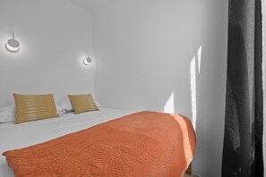 Ein Schlafzimmer mit einem Bett, zwei Kissen, einer Decke und einer Wandleuchte.
