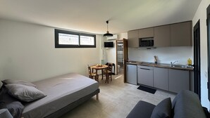 Un espacio habitable compacto con kitchenette, comedor y cama.