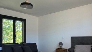 Un dormitorio moderno con cama, sofá, mesita de noche y una mesa con dos macetas de cerámica.