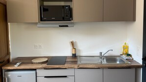 Cocina compacta con microondas integrado, un lavabo y un refrigerador pequeño.