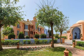 A multi-story building with a courtyard, surrounded by trees and potted plants. - Beachfront Penthouse, Casares (Casares)